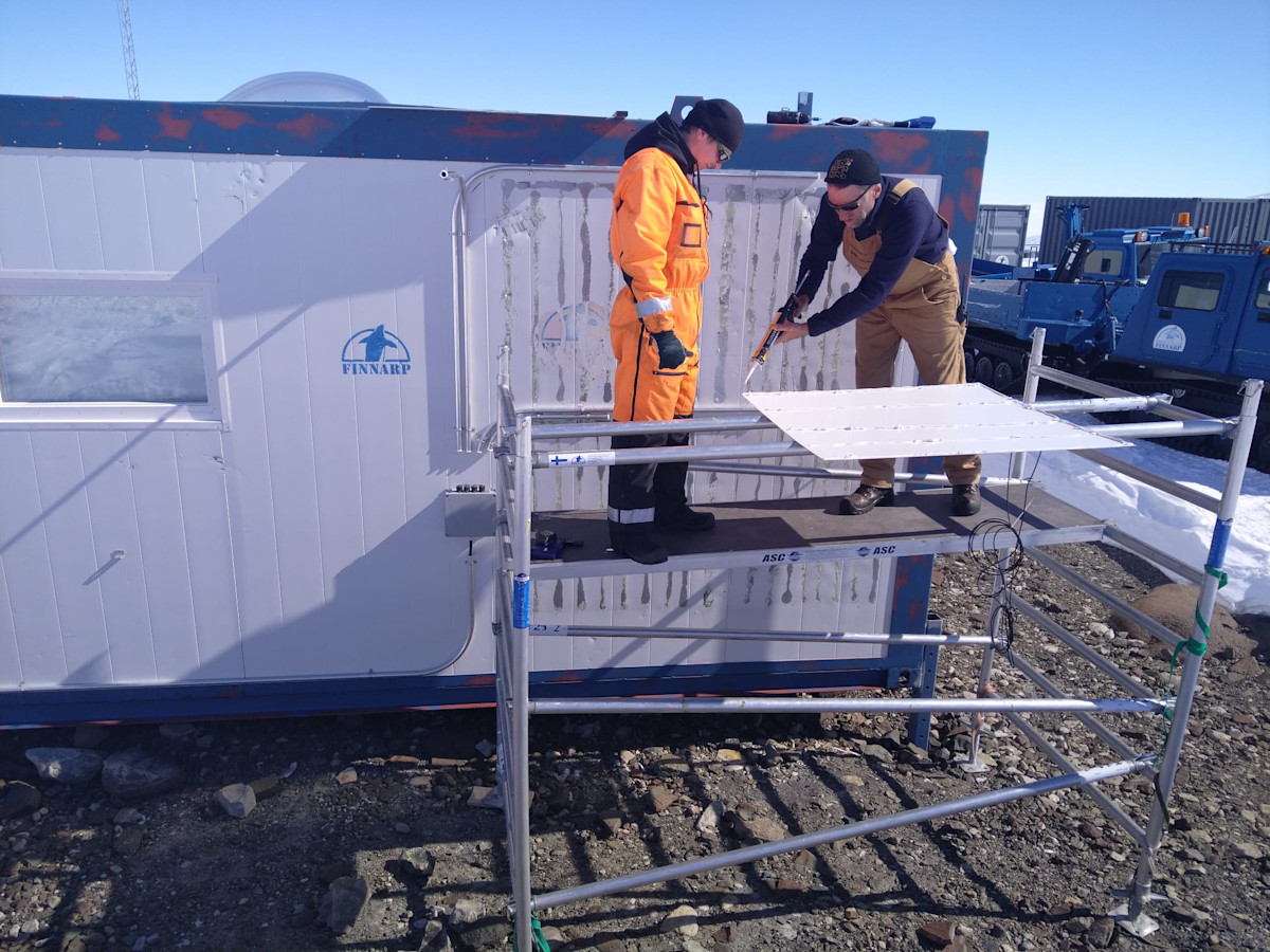 Priit Tisler ja Juho Vehviläinen asentamassa aurinkopaneeleja aseman seinään. 