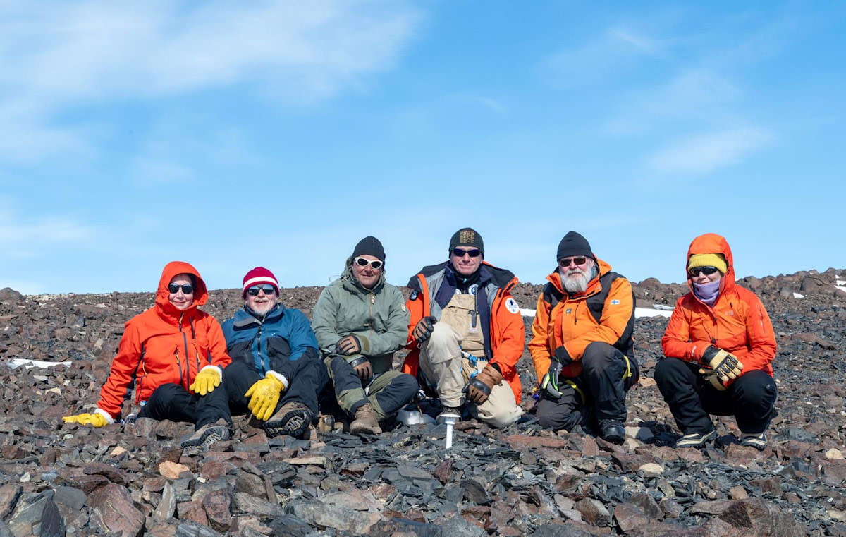 Retkikunnan jäsenet ryhmäkuvassa Etelämantereella. Kaikilla aurinkolasit ja paksut talvivaatteet.
