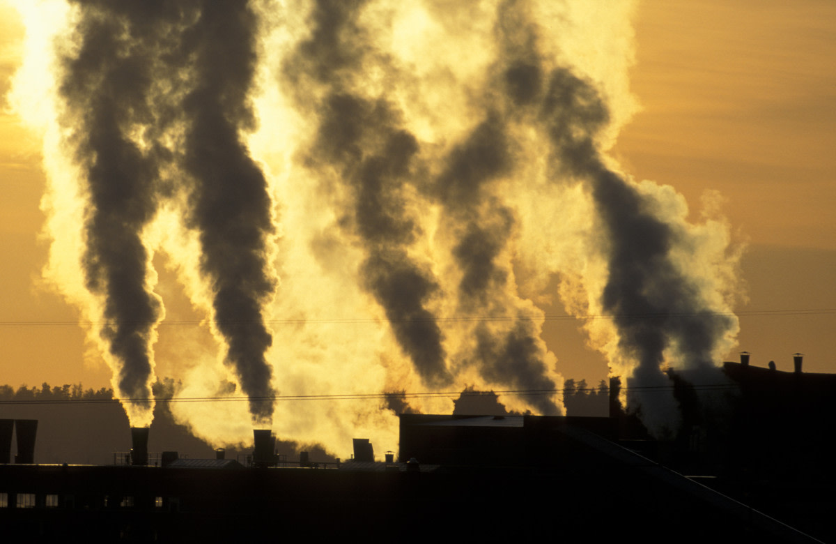 Laitoksen piipuista nousee savupatsaita taivaalle.