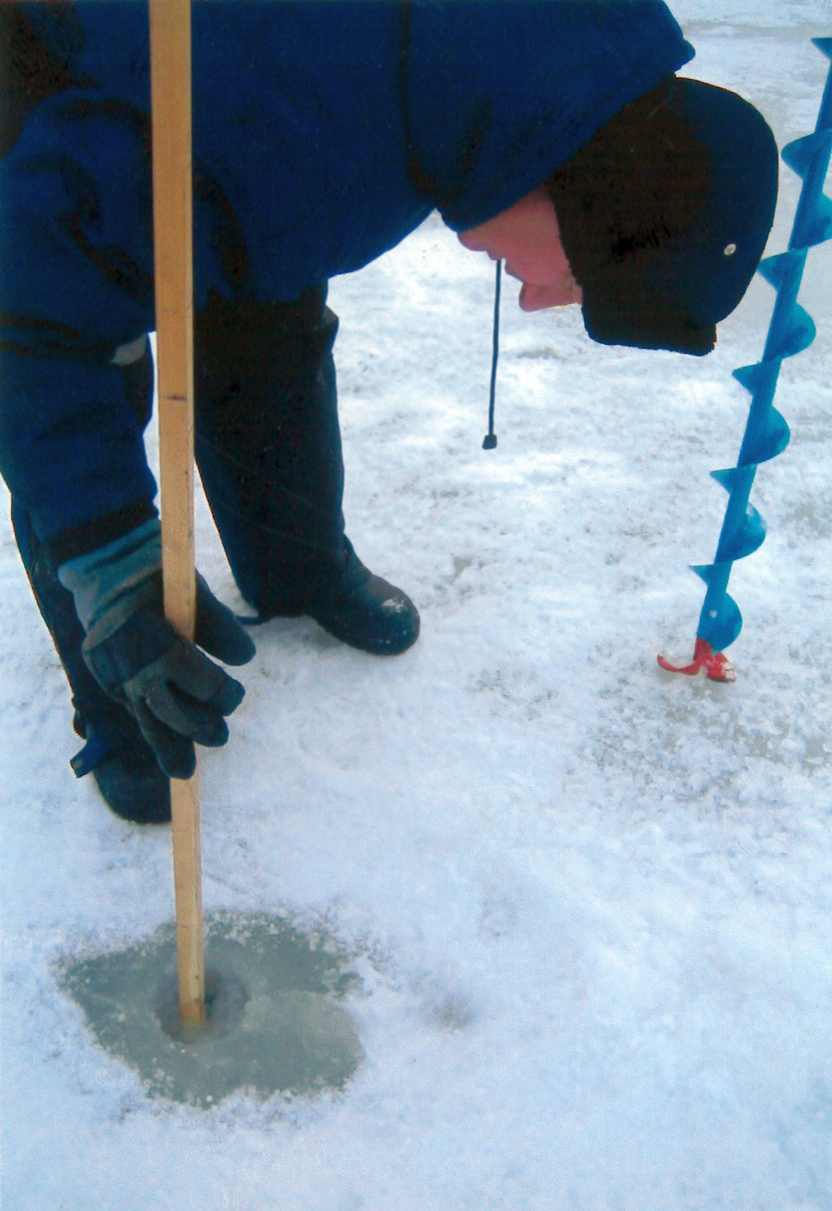 Mies pitää mittatikkua kairanreiässä.