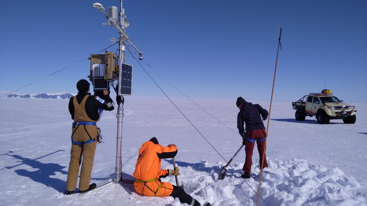 Kolme henkilöä huoltaa sääaseman laitteita.