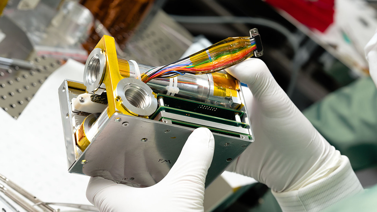 Kuvassa tutkija pitää käsissään Pate-mittalaitetta avattuna, metalliboksin sisällä näkyy mm. johtoja, virtapiiri ja muita mittalaitteen osia