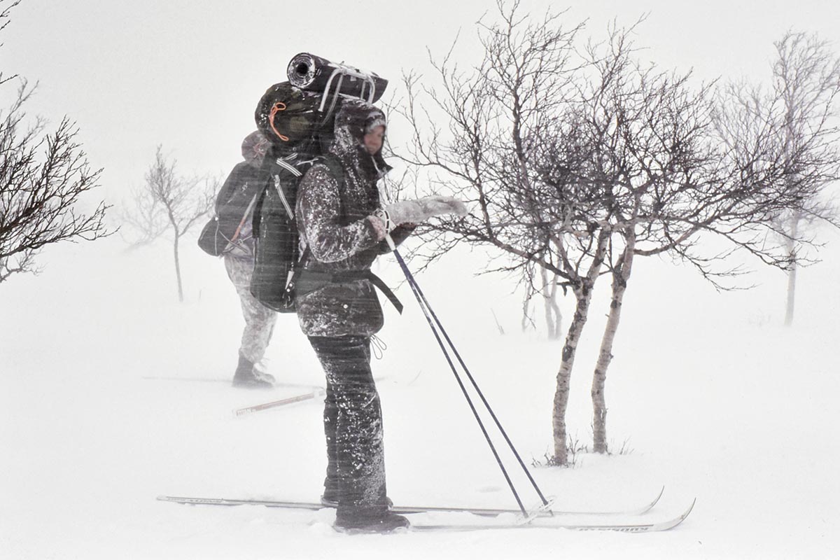 Hiihtäjä lumimyrskyssä, lunta tupruttaa vaakatasossa.