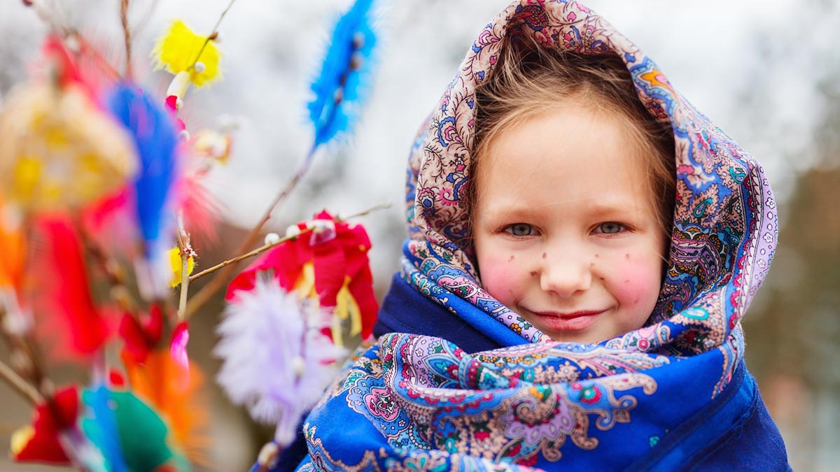 Värikäs virpomisvitsa ja pieni pääsiäisnoita huivi päässä.