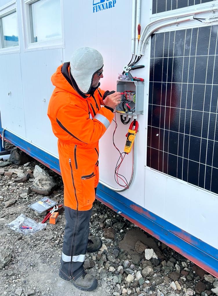 Priit Tisler kytkemässä aurinkopaneelia aseman sähköjärjestelmään. 