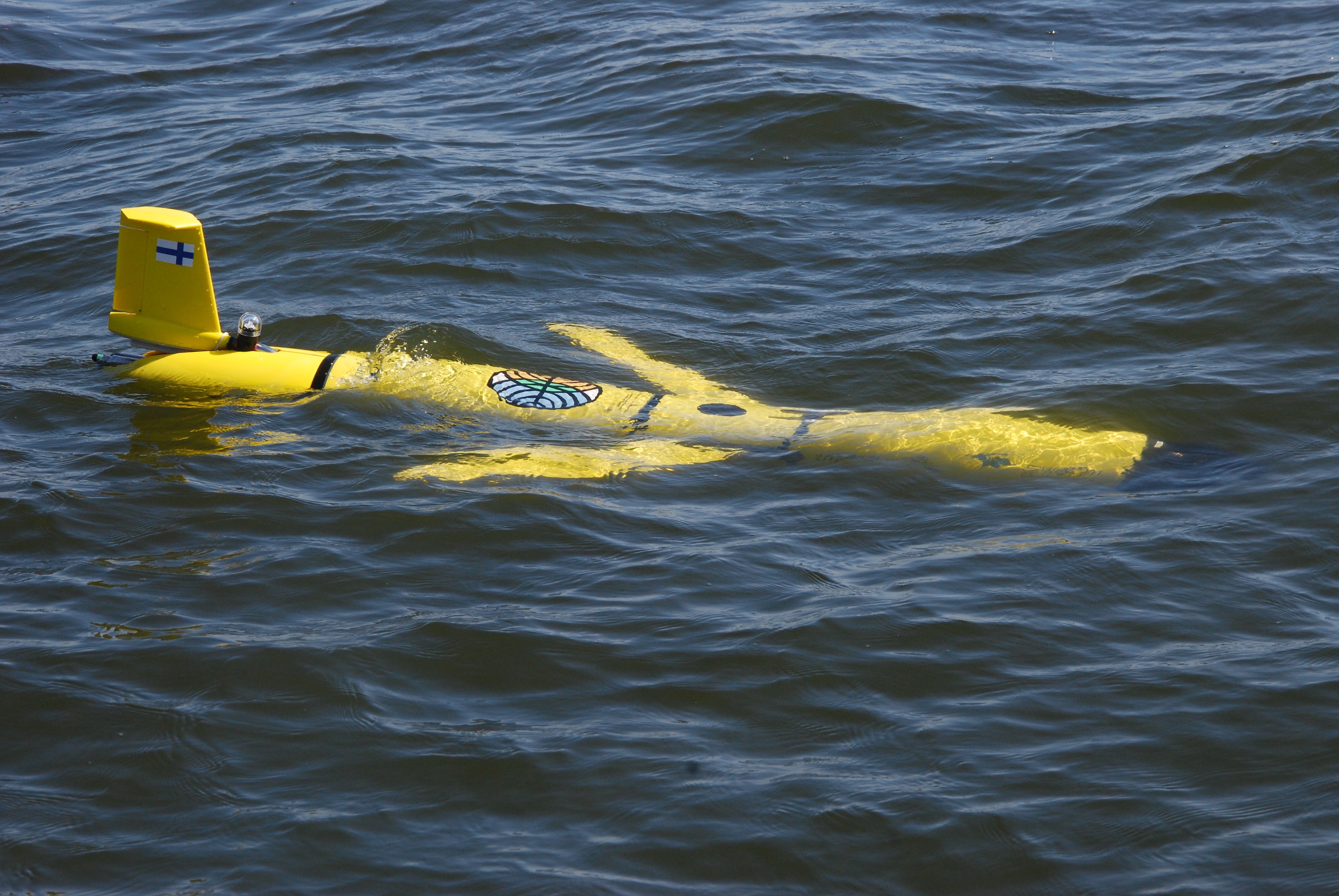 Lentokoneen muotoinen keltainen mittalaite ui veden alla.