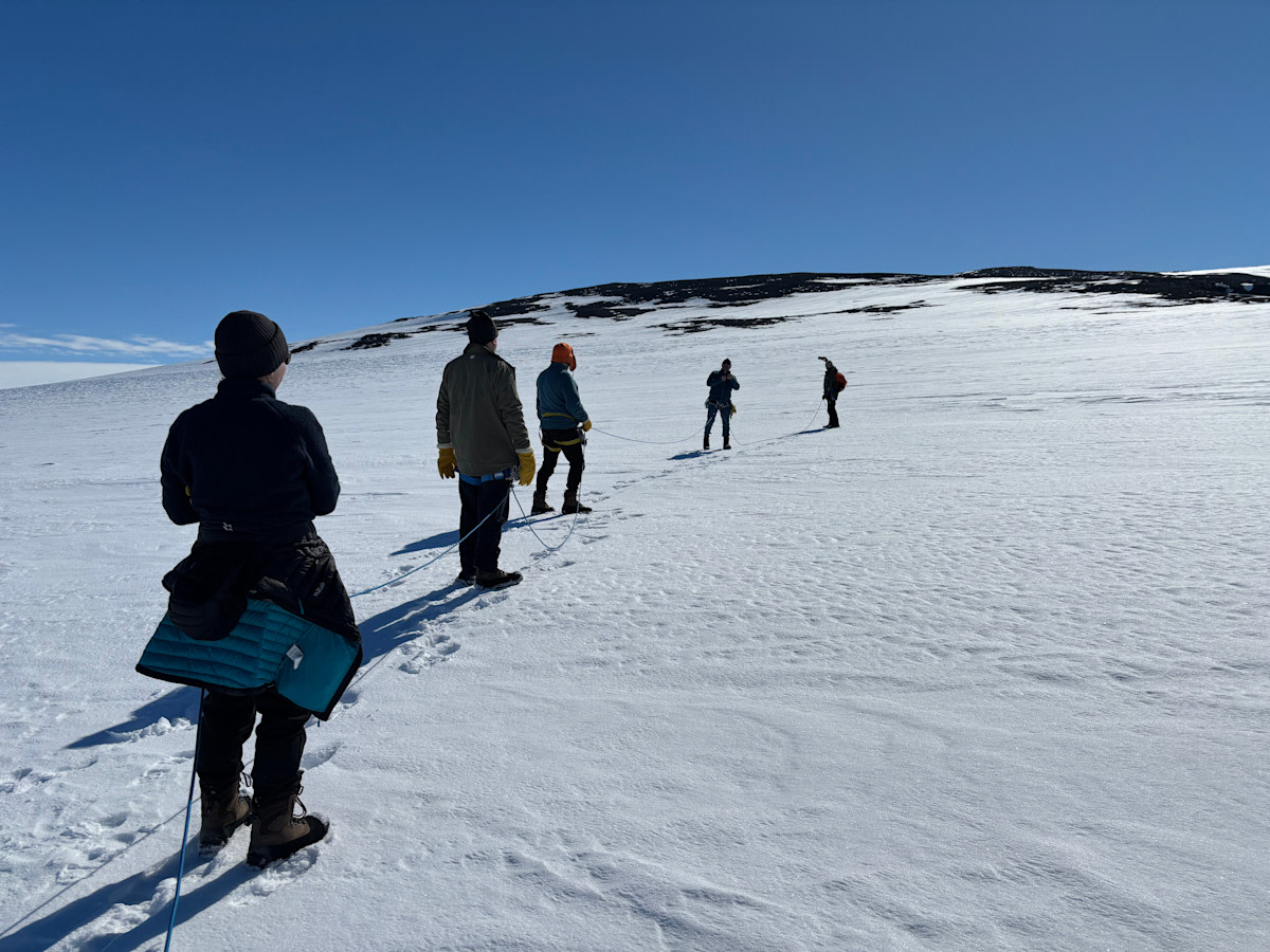 Retkikunnan jäsenet kävelevät jonossa jäätiköllä.