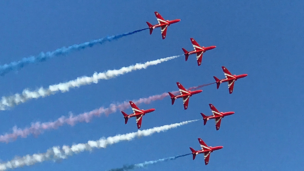 Sinisellä taivaalla seitsemän Red Arrows -konetta lentonäytöskuviossa.
