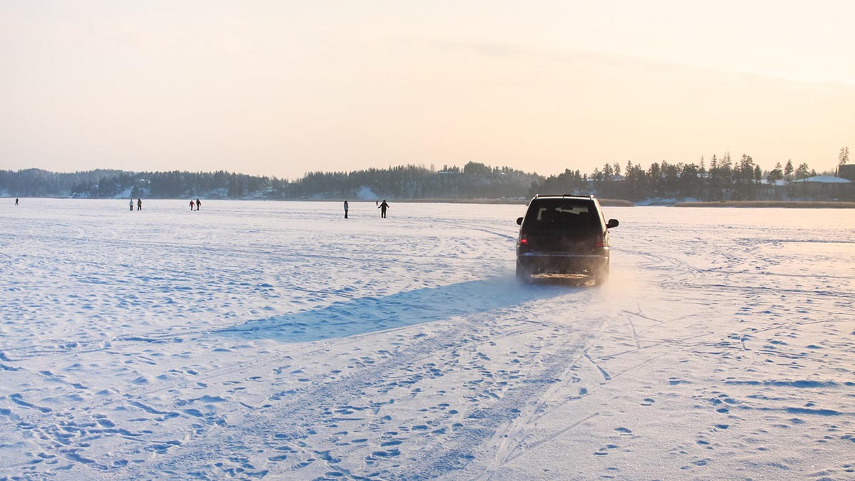 Henkilöauto ajamassa jäällä talvisessa maisemassa.
