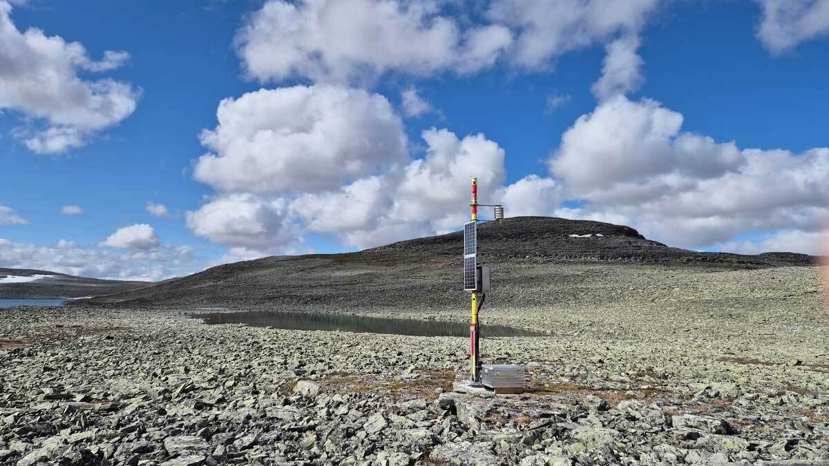 Kivikkoisella ylänköalueella seisoo 4.5 metriä korkea pylväs, johon on asennettu aurinkopaneeleja sekä meteorologisia mittalaitteita. Aseman takana siintää Loassonibba-tunturi.