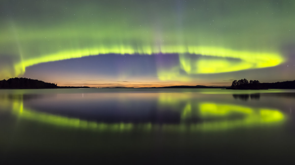 Revontulet veden yllä ja heijastuneena veden pintaan.