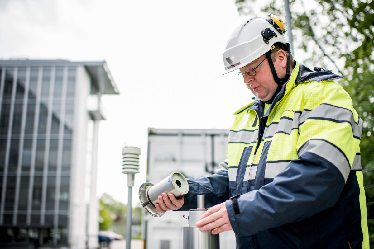 Tutkija asentaa ilmanlaadun mittalaitetta toimintaan.