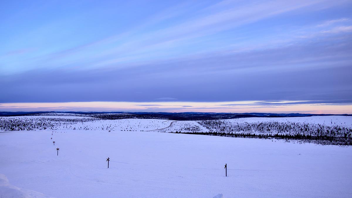 Talvisen avara tunturimaisema, johon merkitty kulkureitti moottorikelkalle.