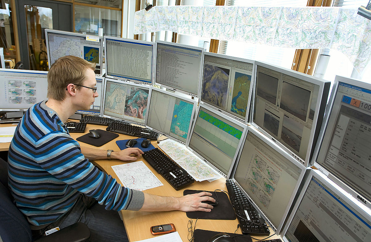 Meteorologi on työssään useiden tietokonenäyttöjen ympäröimä.