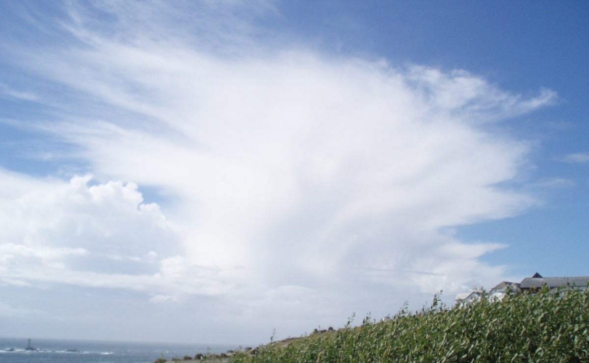 Ukkospilvi on merellä. Siinä on jääkiteistä muodostunut huntu ja kumpuileva alaosa.