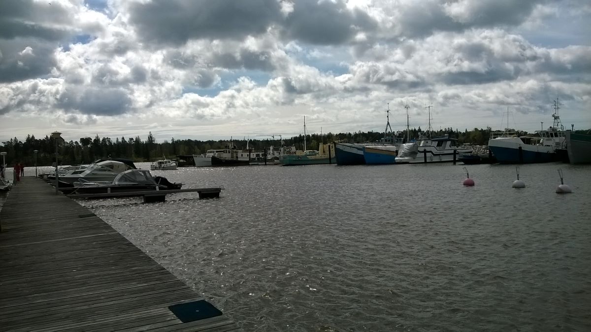 Venesatama veneineen ja laivoineen. Taivaasta reilusti puolet on pilvien peitossa.