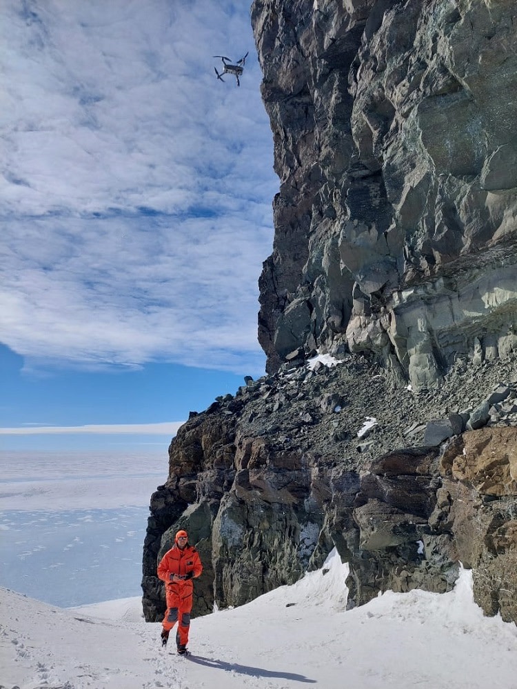 Aleksi lentää droonia kallioseinämän läheisyydessä basalttikerrosten kartoittamista varten. 