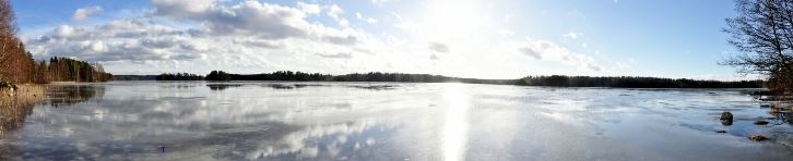 Aurinko paistaa tyyneen vedenpintaan.