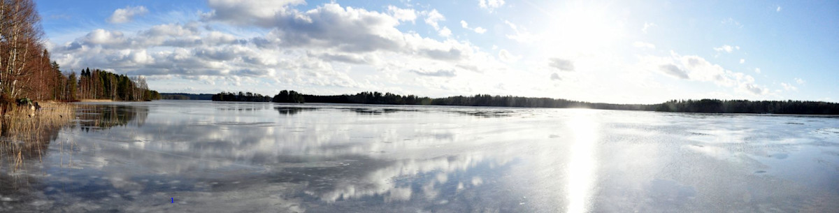 Aurinko paistaa tyyneen vedenpintaan.